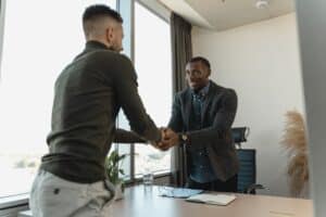 Two men shaking hands over a desk.